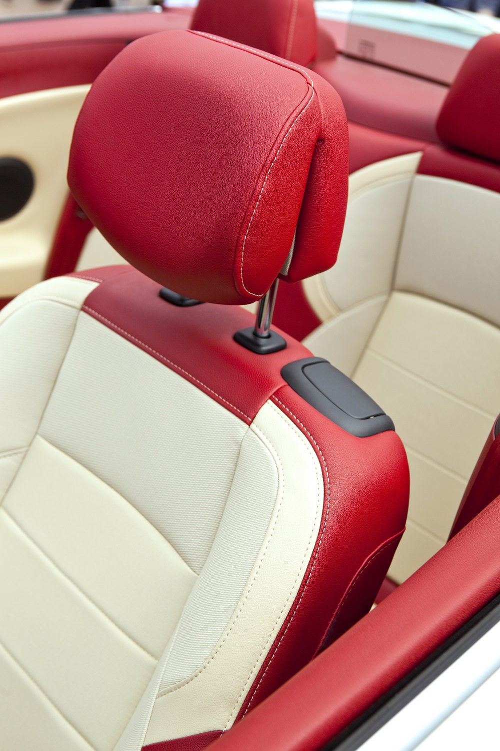 Close-up of the front seats in a convertible car with red and cream leather, showcasing premium car interior upholstery in New Orleans.