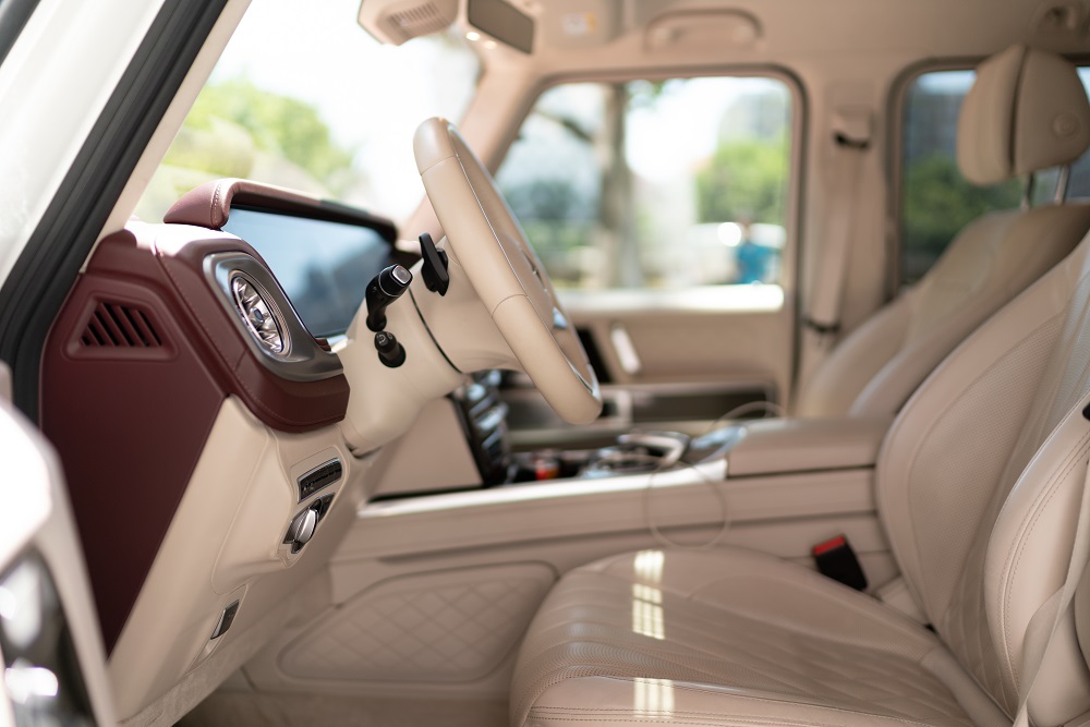  Interior view of a luxury vehicle, highlighting beige leather seats, a dashboard with a large display screen, and a steering wheel—showcasing the premium craftsmanship of Custom Truck and SUV Builds in Metairie.