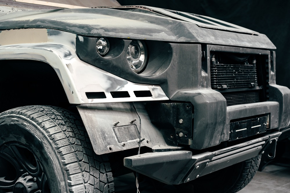 Close-up of the front left side of a car under repair at Custom Cars in Mandeville, showing exposed metal, missing parts, and unpainted bodywork—a scene common in LA’s thriving custom auto scene.