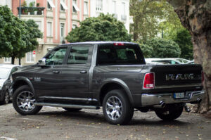 A gray RAM 1500 pickup truck, fresh from an engine tuneup, is parked on a street near trees and a building with balconies in the background.